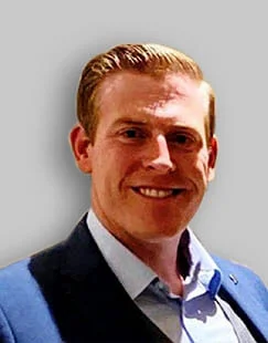 Clayton Cruse, Attorney specializing in Crypto, Bitcoin, and NFT matters at Sullivan for IRS Matters, smiling confidently in professional attire within a modern office environment.